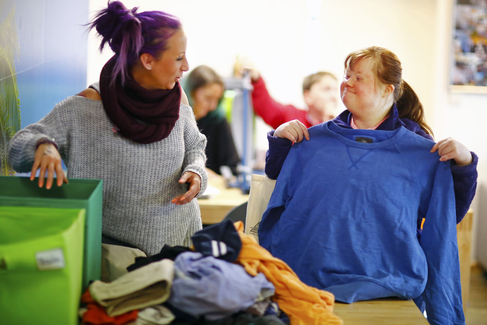 Zwei Frauen, eine davon mit Down-Syndrom, sortieren gemeinsam Wäsche.