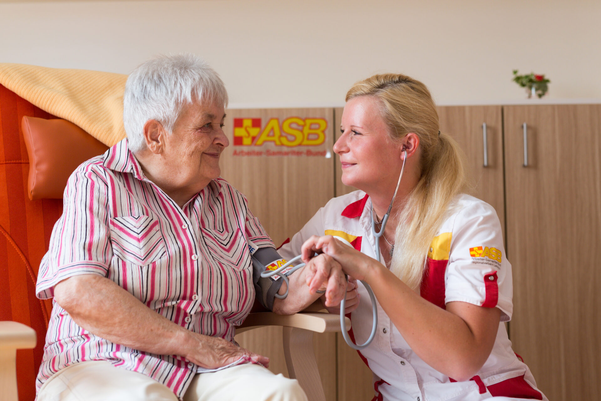 Eine Pflegekraft prüft bei einer Seniorin den Blutdruck.