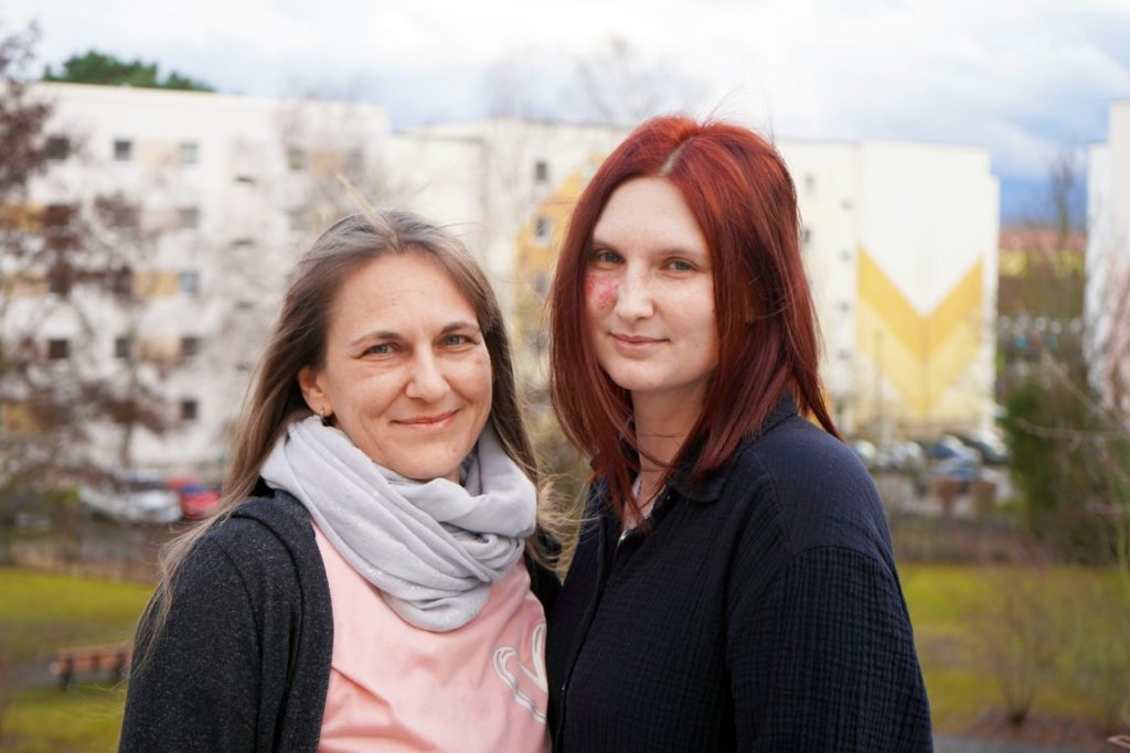 Zwei Damen, Mutter und Tochter, schauen lächelnd in die Kamera.