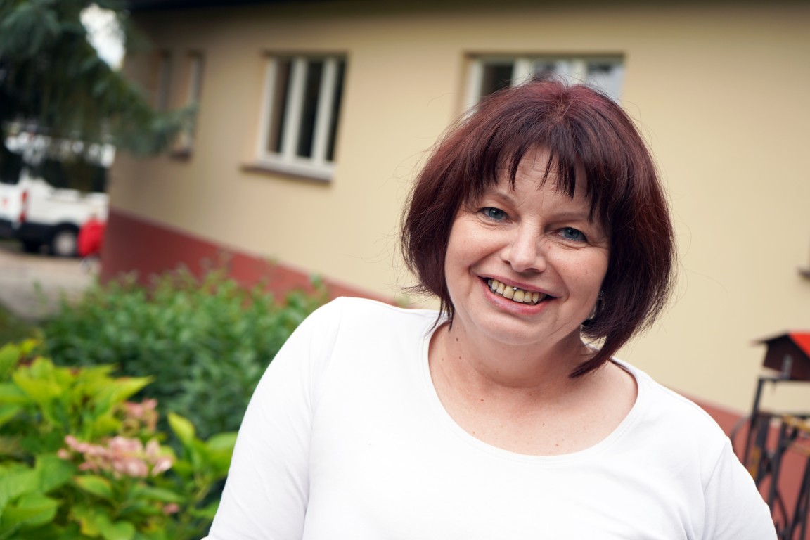 Eine Dame schaut freundlich in die Kamera und lächelt.